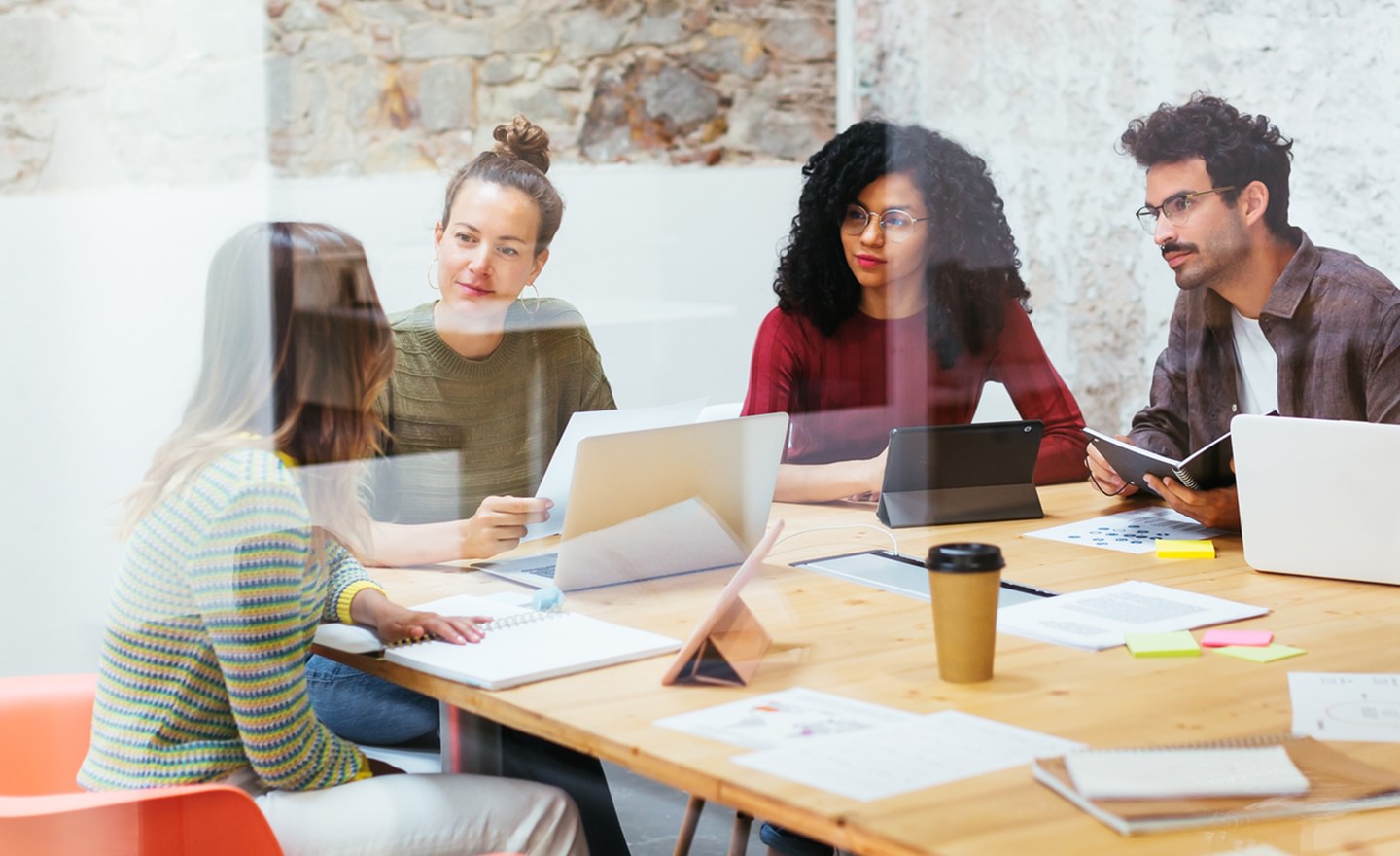 Group of coworkers at a conference table seen through glass