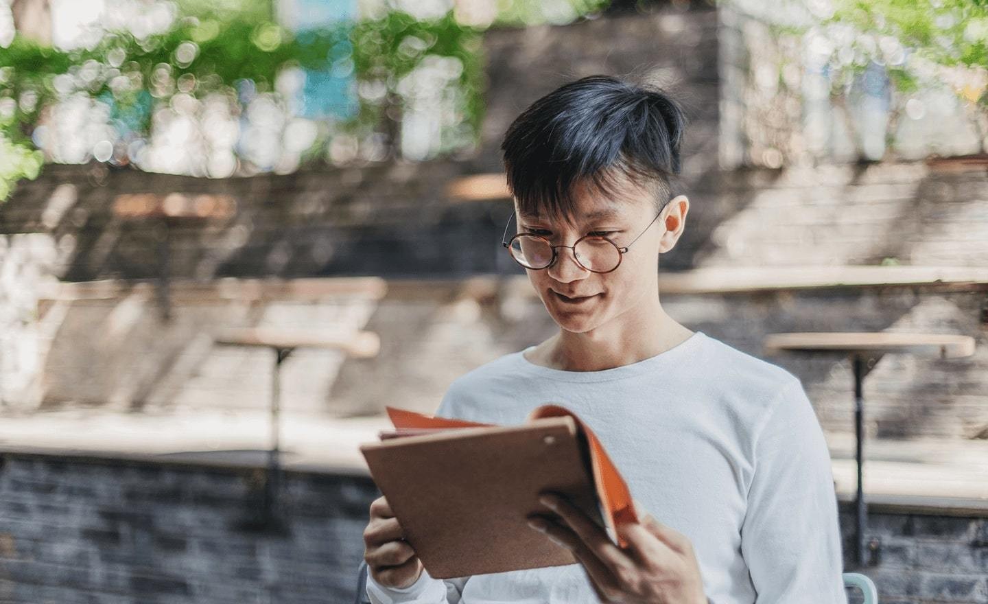 Man outside reading with glasses