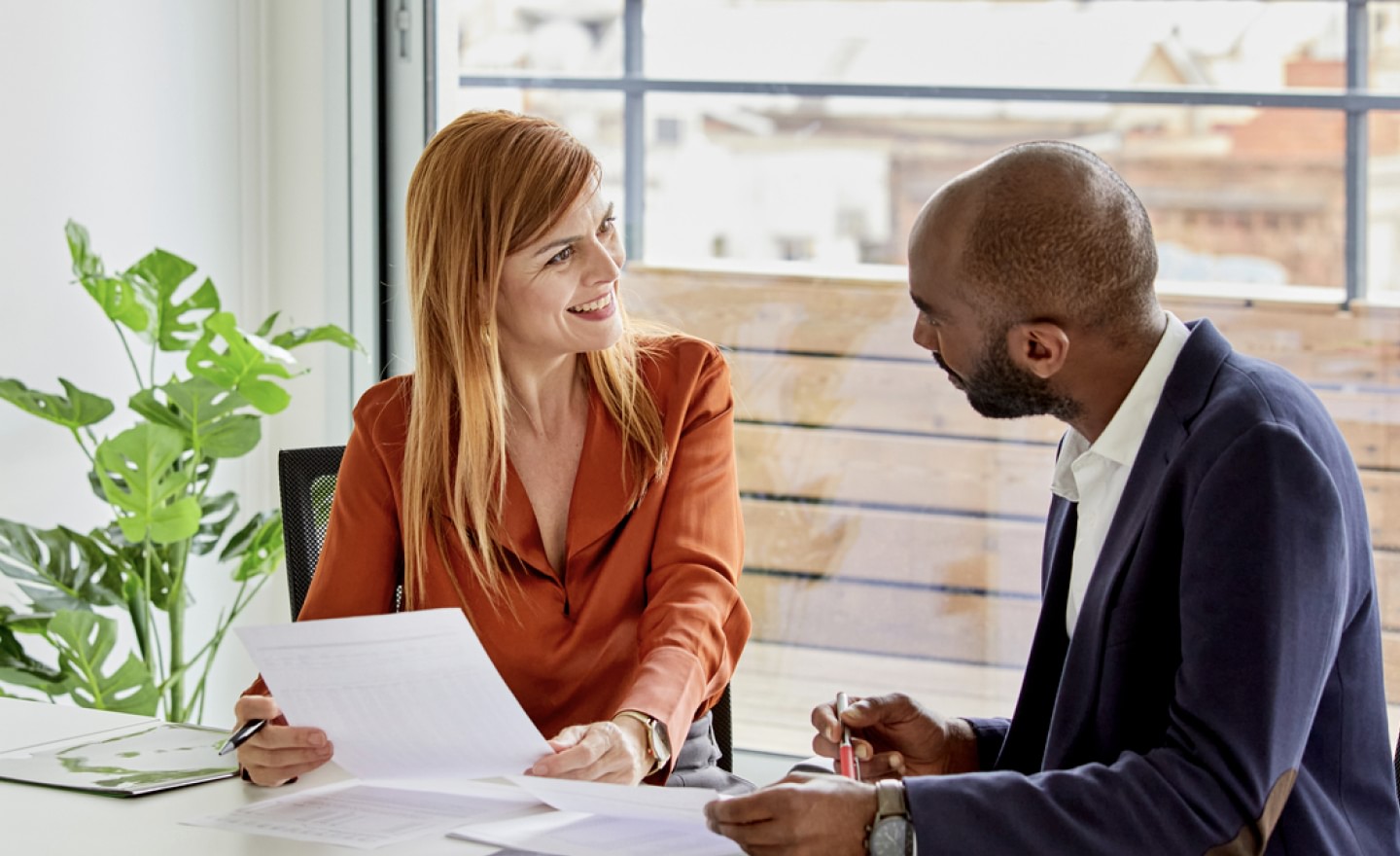 Photo of woman colleague holding paper facing male colleague smiling