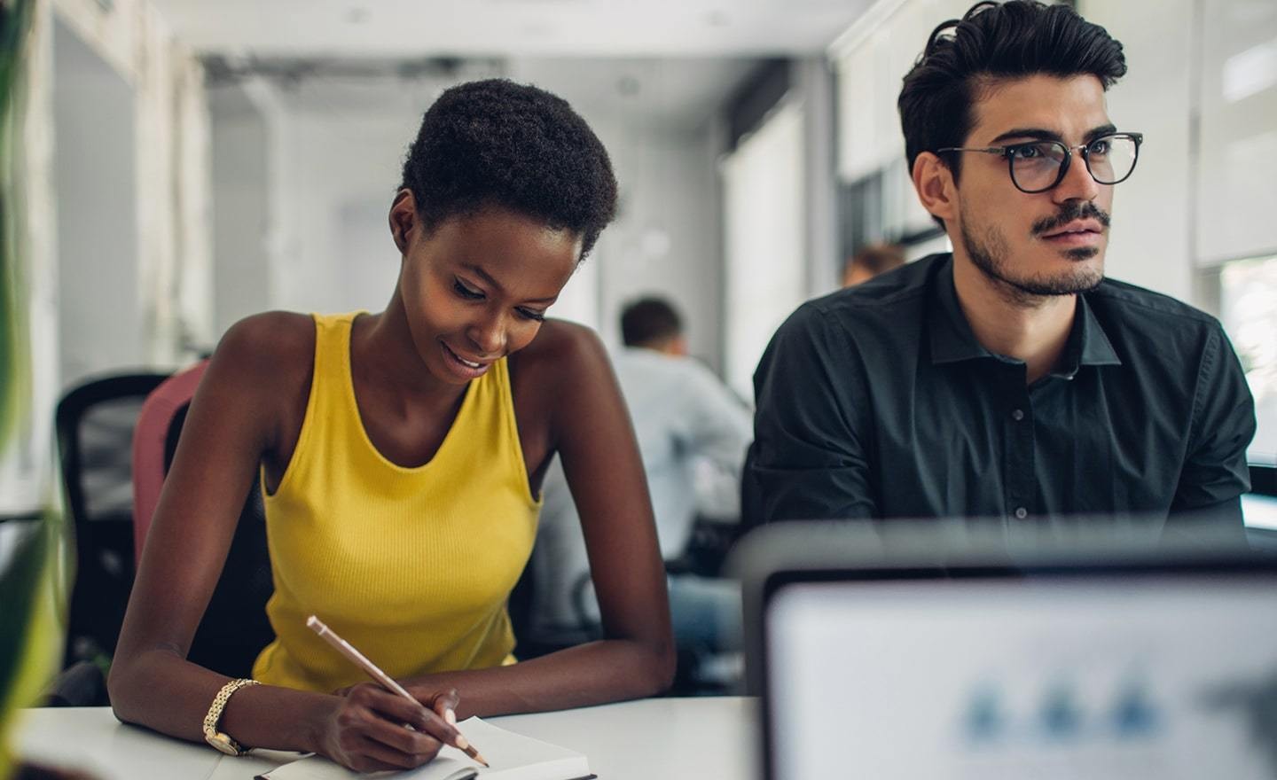 Two coworkers sitting at a conference table in an open office