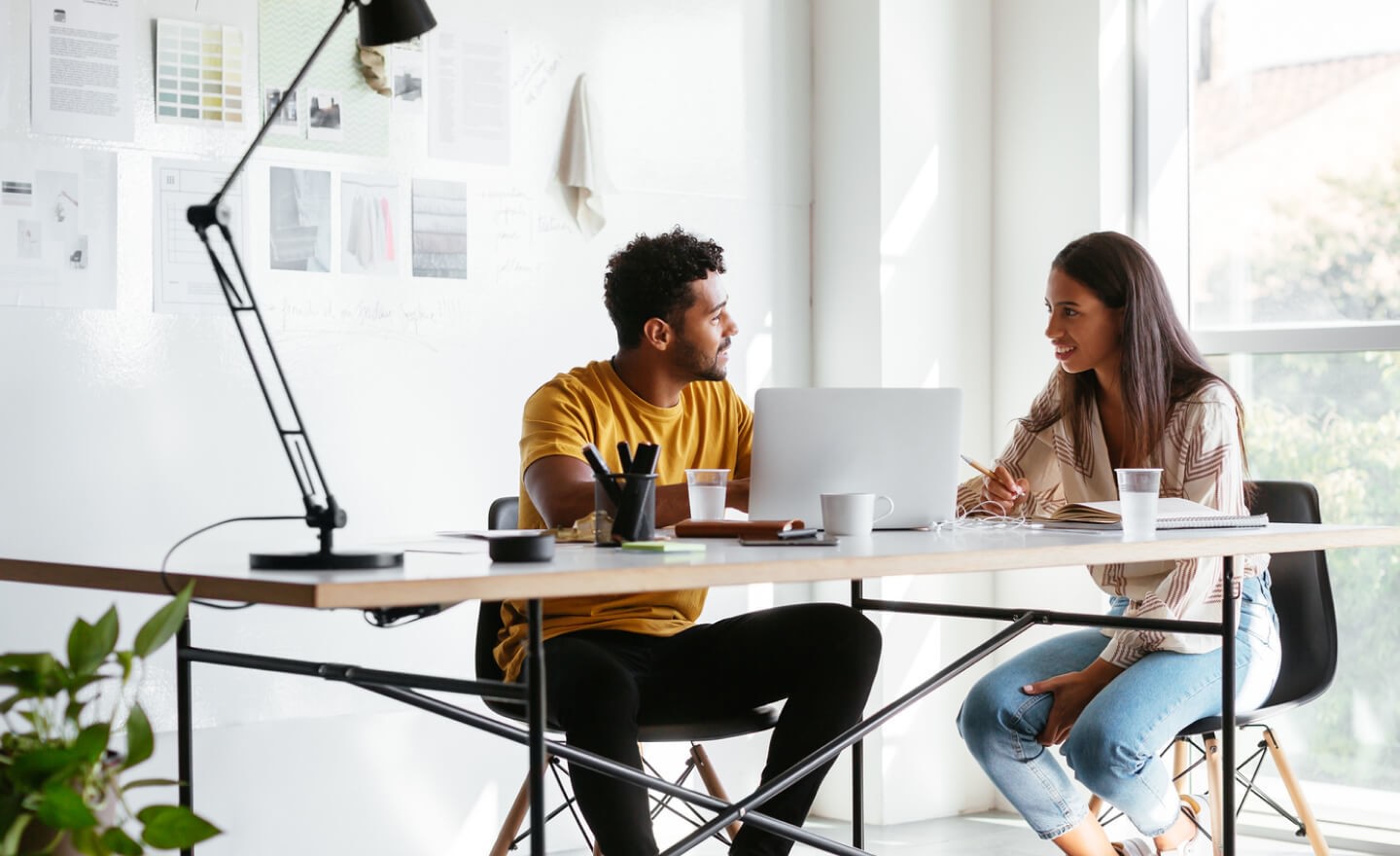 Two coworkers sitting at a table by a window