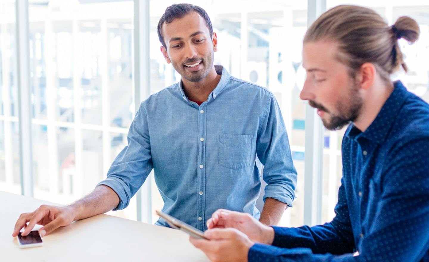 Two men looking at a tablet in a conference room