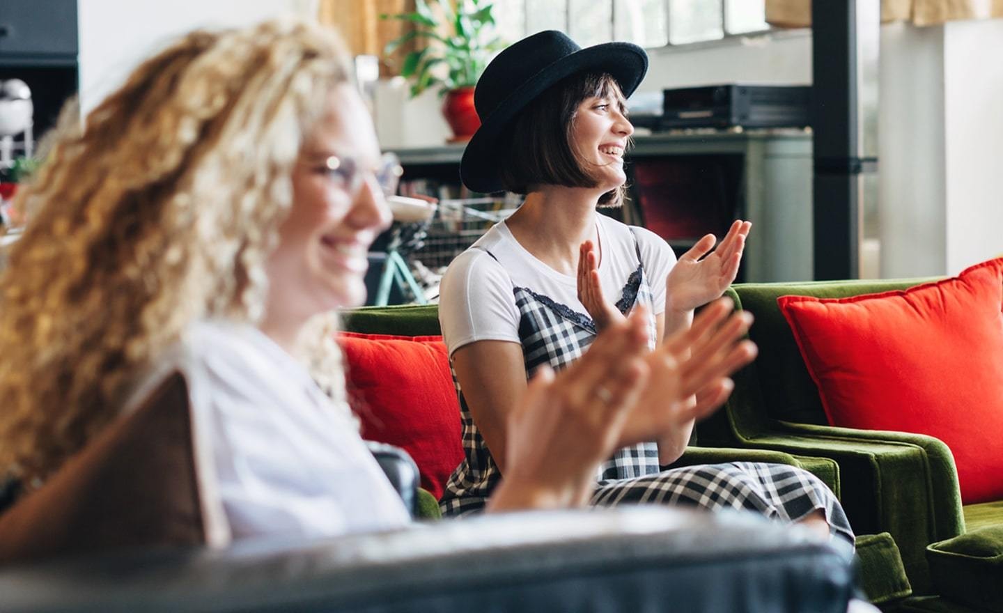 Two women sitting on couch clapping