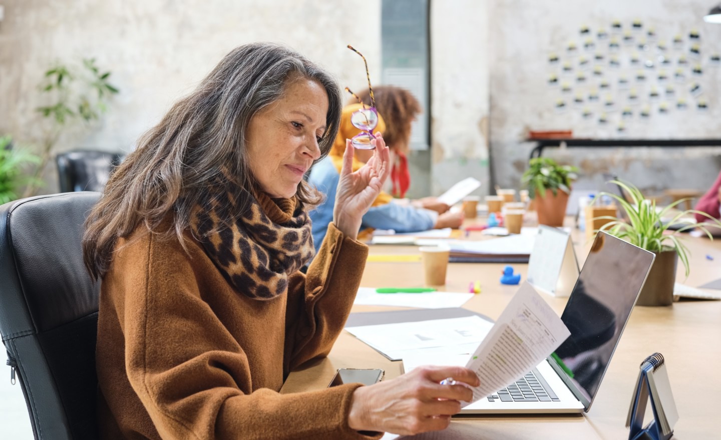 Woman holding glasses reading report