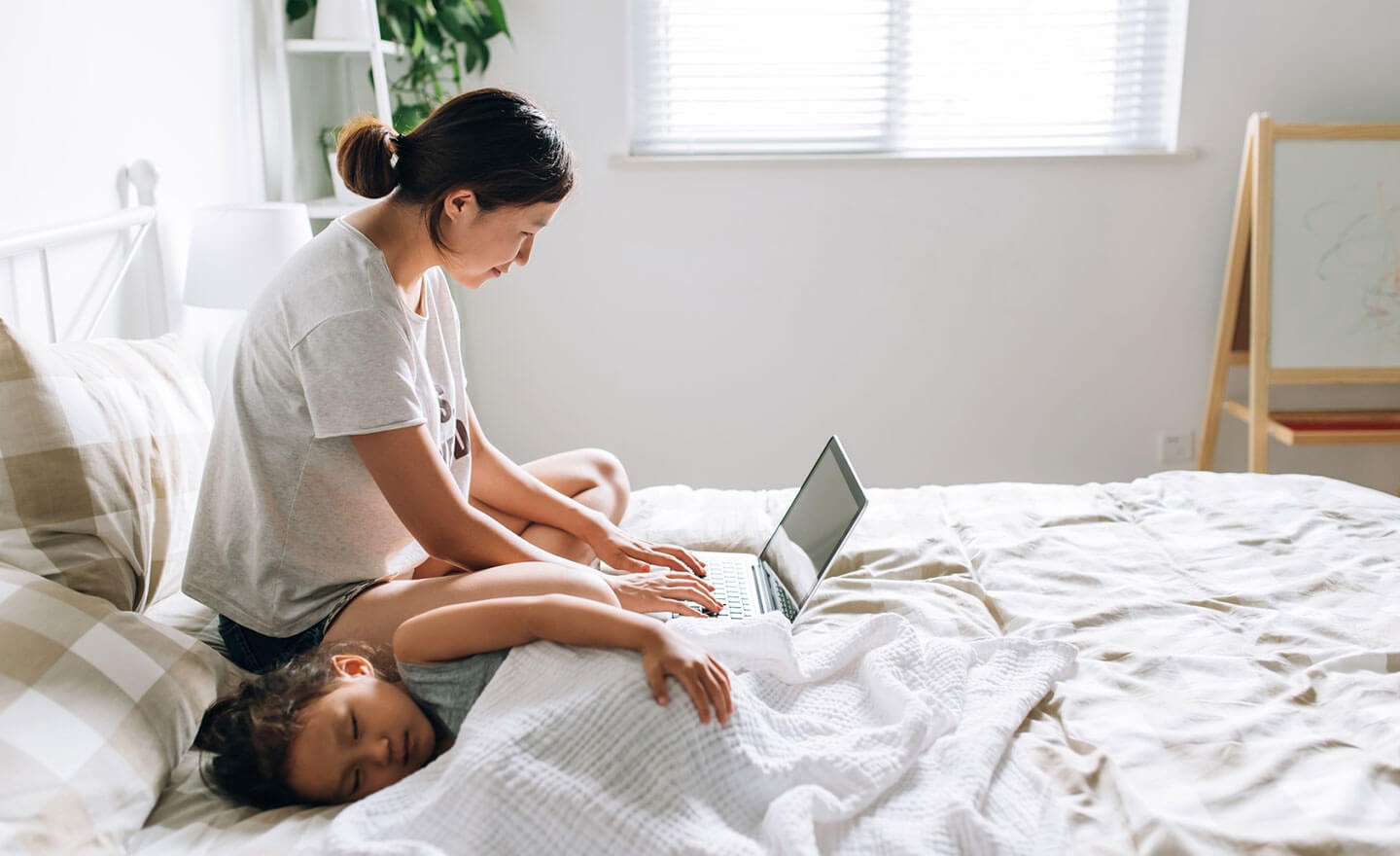 Woman working from home with sick child in bed