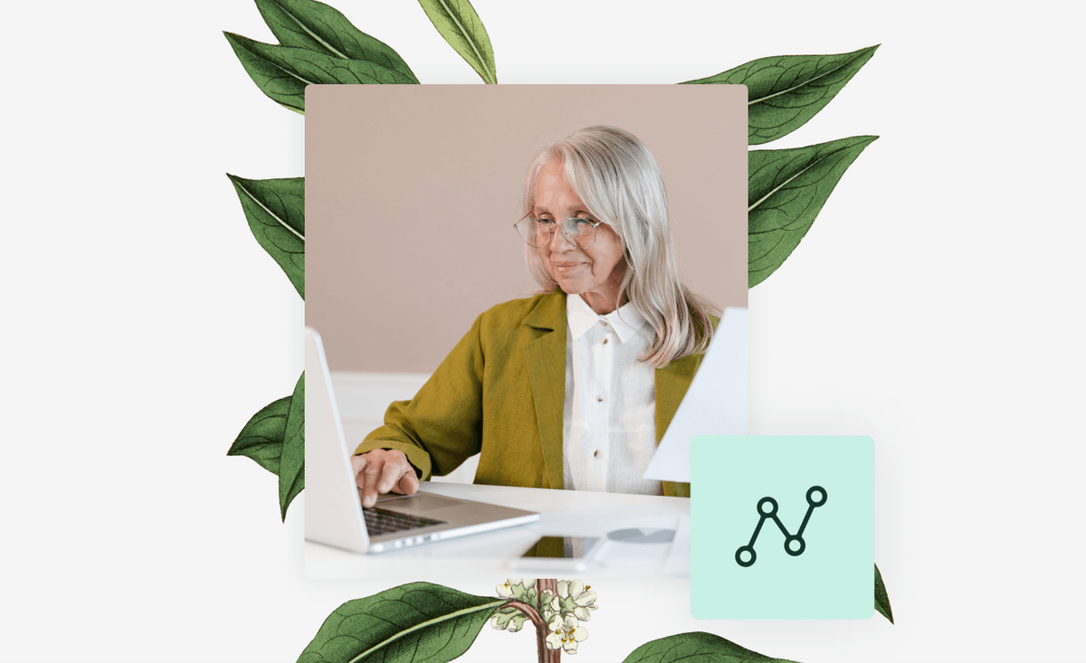 Older woman working on laptop with botanical plant behind