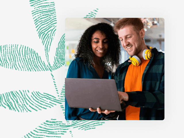 Photo of two coworkers standing with a laptop and talking