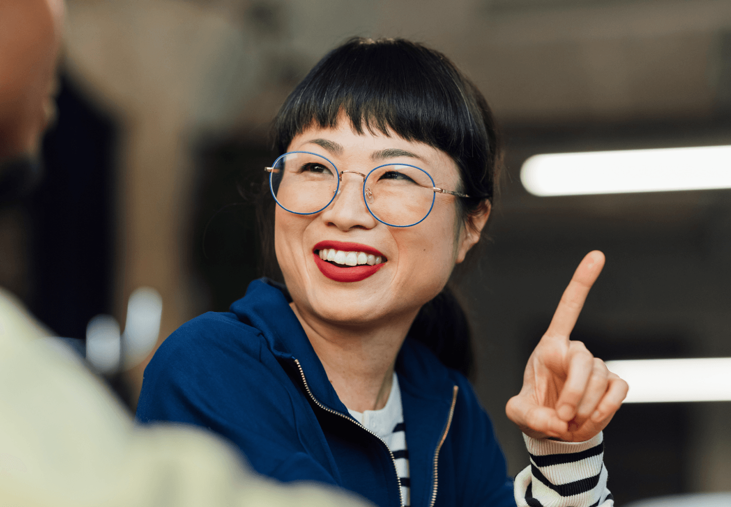 Woman wearing glasses smiling while pointing to the right